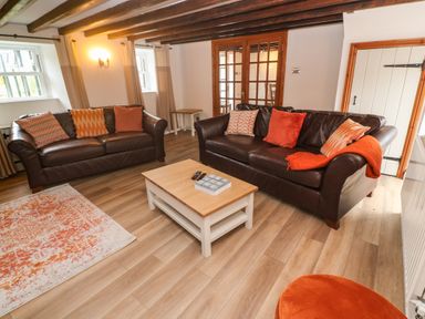 A living room with two brown sofas and a wooden coffee table at Trevedran Cottage in St Buryan