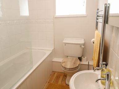 A bathroom with a bathtub toilet and sink with soap bottles at Trevedran Cottage in St Buryan