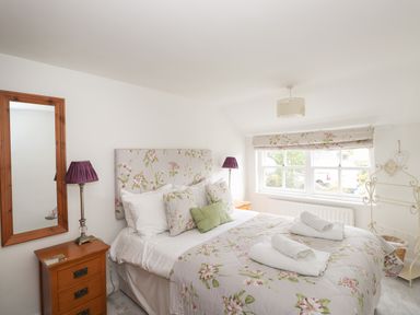 A bedroom with a double bed floral bedding bedside tables and a window at Bay Tree Cottage in Ambleside