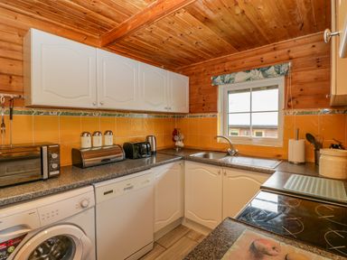 A kitchen with white cabinets a window a sink and various appliances at Orchard Lodge in Hockworthy near Sampford Peverell Devon