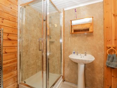 A bathroom with a glass enclosed shower a pedestal sink and a mirror cabinet at Orchard Lodge in Hockworthy near Sampford Peverell Devon