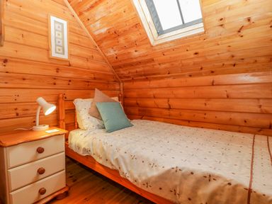 A bedroom with wooden walls a single bed a bedside table and a skylight at Orchard Lodge in Hockworthy near Sampford Peverell Devon