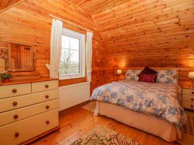 A bedroom with a double bed two bedside tables and a chest of drawers with a mirror at Orchard Lodge in Hockworthy near Sampford Peverell Devon