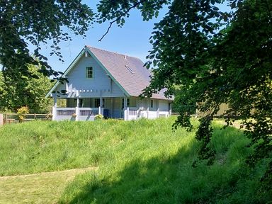 A house with a porch surrounded by grass and trees at Orchard Lodge in Hockworthy near Sampford Peverell Devon