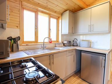 A kitchen with a stove microwave sink toaster kettle and small fridge at Clover Lodge Theberton near Leiston