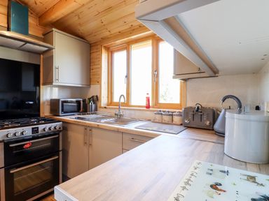 A kitchen with a stove oven microwave sink toaster kettle and canisters at Clover Lodge in Theberton near Leiston