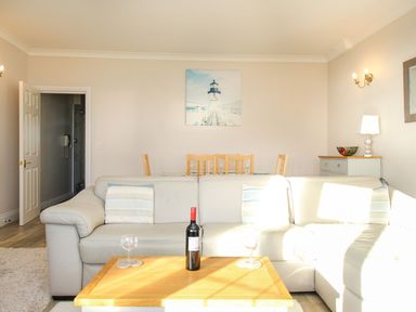 A living room with a gray sofa and wooden coffee table with a wine bottle and glasses at Ocean Watch 5 in Greenhill