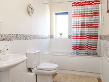 A bathroom with a bathtub a toilet a sink and a window at Ocean Watch 5 in Greenhill