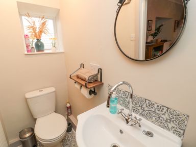 A bathroom with a toilet sink and round mirror at Castle Keep in Norham