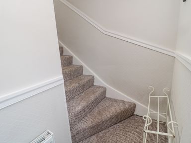 A carpeted staircase with a white metal rack and radiator in a hallway at Castle Keep in Norham