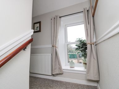 A stairway landing with a window featuring curtains a plant and a vase at Castle Keep in Norham