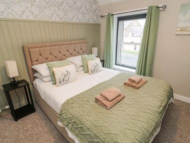 A bedroom with a double bed green curtains and a window at Castle Keep in Norham