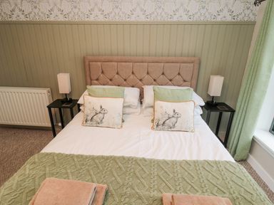 A bedroom with a double bed with cushions and bedside lamps at Castle Keep in Norham