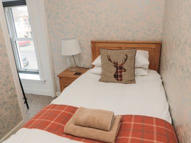 A bedroom with a single bed a wooden headboard a bedside table with a lamp and folded towels at Castle Keep in Norham