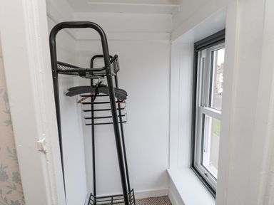 A small room with a black metal clothes rack and a window at Castle Keep in Norham