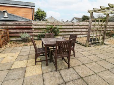 An outdoor patio with a wooden table and four chairs surrounded by wooden fencing and a pergola at Castle Keep in Norham