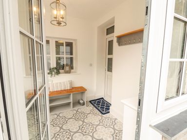 An entrance hall with a bench and coat hooks at The Old Post House at Low Stott Park