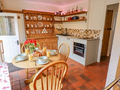 A kitchen with a wooden dining table set with bowls glasses and croissants at Rose Cottage in Holcombe Teignmouth