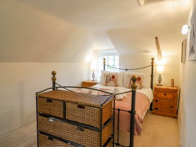 A bedroom with a metal bed frame pillows and bedside tables with lamps at Rose Cottage in Holcombe Teignmouth
