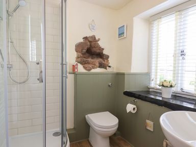 A bathroom with a shower cubicle toilet sink and window with blinds at Rose Cottage in Holcombe Teignmouth