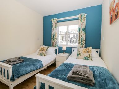 A bedroom with two single beds with floral pillows and folded towels at Claife Heights in Windermere