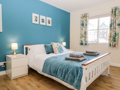 A bedroom with a white bed and blue blanket with two bedside tables and lamps at Claife Heights in Windermere