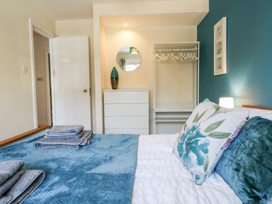 A bedroom with a bed with pillows and towels a white dresser and an open wardrobe at Claife Heights in Windermere