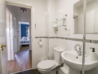 A bathroom with a toilet sink and mirror looking into a bedroom at Claife Heights Windermere