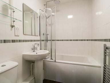 A bathroom with a bathtub shower combination a pedestal sink a toilet and a towel radiator at Claife Heights in Windermere