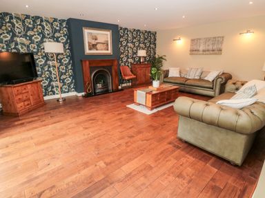 A living room with two sofas a wooden coffee table a fireplace and a television at Calm Skies in Scremerston near Berwick-Upon-Tweed
