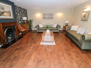 A living room with two green sofas a wooden coffee table and a fireplace at Calm Skies Scremerston near Berwick-Upon-Tweed