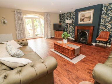 A living room with two sofas a wooden coffee table with a plant a fireplace and a television at Calm Skies Scremerston near Berwick-Upon-Tweed