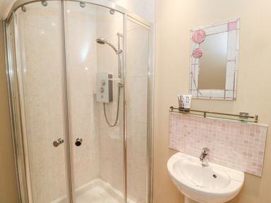 A bathroom with a glass shower enclosure a sink and a decorative mirror at Calm Skies Scremerston near Berwick-Upon-Tweed