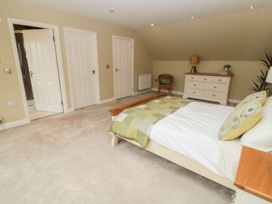 A bedroom with a bed a dresser a chair and three doors at Calm Skies in Scremerston near Berwick-Upon-Tweed