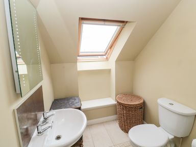 A bathroom with a sink toilet wicker basket and skylight window at Calm Skies in Scremerston near Berwick-Upon-Tweed