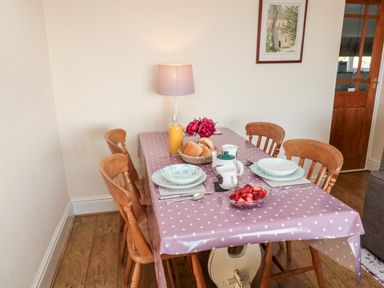 A dining table set with plates cups bread a jug of juice and a bowl of strawberries at Healey Farm Cottage in Rothbury