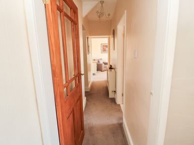 A hallway with a wooden door partially open leading to a room with a chair at Healey Farm Cottage in Rothbury