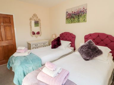 A bedroom with two single beds with red headboards and folded towels on the beds at Healey Farm Cottage in Rothbury