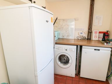 A utility room with a fridge, washing machine, and freezer under a wooden countertop at Healey Farm Cottage in Rothbury