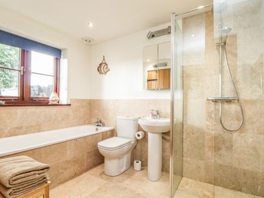 A bathroom with a bathtub toilet sink and glass-enclosed shower at Polurrian House in Cury near Mullion