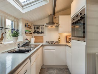 A kitchen with a sink stove oven cooking utensils and a skylight at Smugglers Cottage in Christchurch