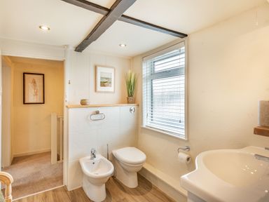 A bathroom with a bidet toilet sink and window blinds at Smugglers Cottage in Christchurch