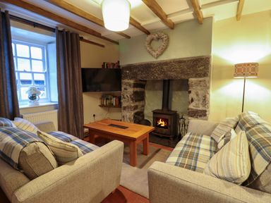 A living room with two sofas a wooden coffee table a stone fireplace with a wood stove and a heart decoration Bwthyn Y Bugail Manod near Blaenau Ffestiniog