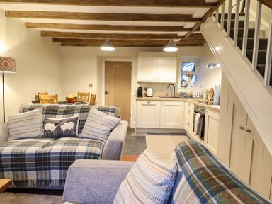 An open living room with sofas and cushions next to a kitchen and dining area at Bwthyn Y Bugail Manod near Blaenau Ffestiniog
