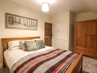 A bedroom with a wooden bed and wardrobe a door and a painting above the bed at Bwthyn Y Bugail Manod near Blaenau Ffestiniog