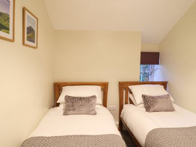 A bedroom with two single beds with wooden headboards and pillows at Bwthyn Y Bugail in Manod near Blaenau Ffestiniog
