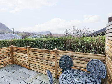 A patio with a metal table and chairs and wooden fencing surrounding it at Bwthyn Y Bugail in Manod near Blaenau Ffestiniog