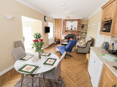 A dining table with four plates and a vase of flowers near a living room with armchairs and a fireplace at The Water's Edge in Boyle County Roscommon