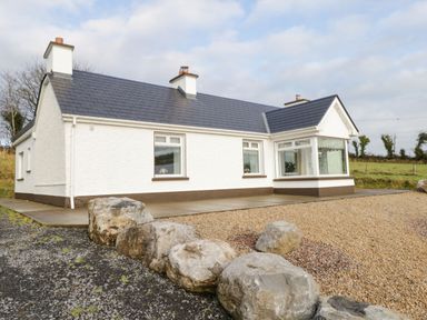 Exterior view of a white house with slate roof and large stones in front at The Water's Edge in Boyle County Roscommon