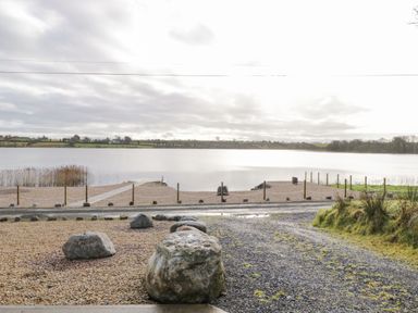A lakeside view with a gravel path and large rocks near the water at The Water's Edge in Boyle County Roscommon